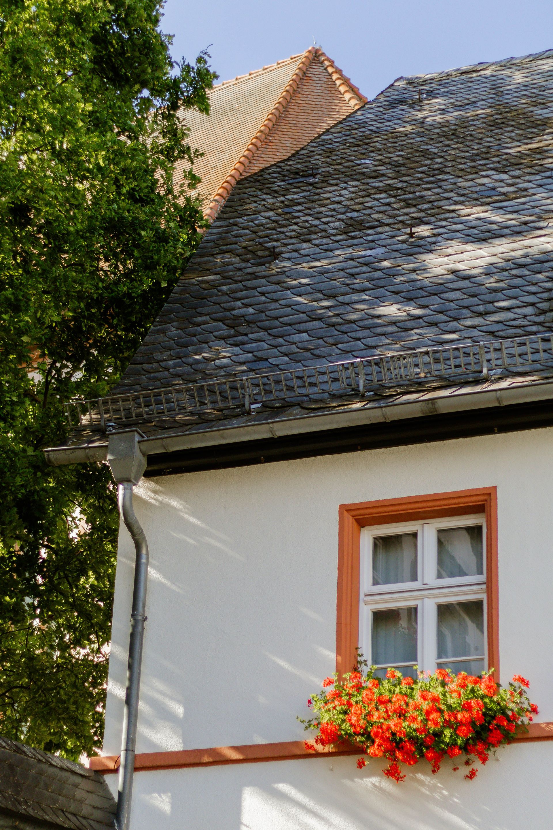 Quaint European house exterior with slate roof and vibrant flower box.