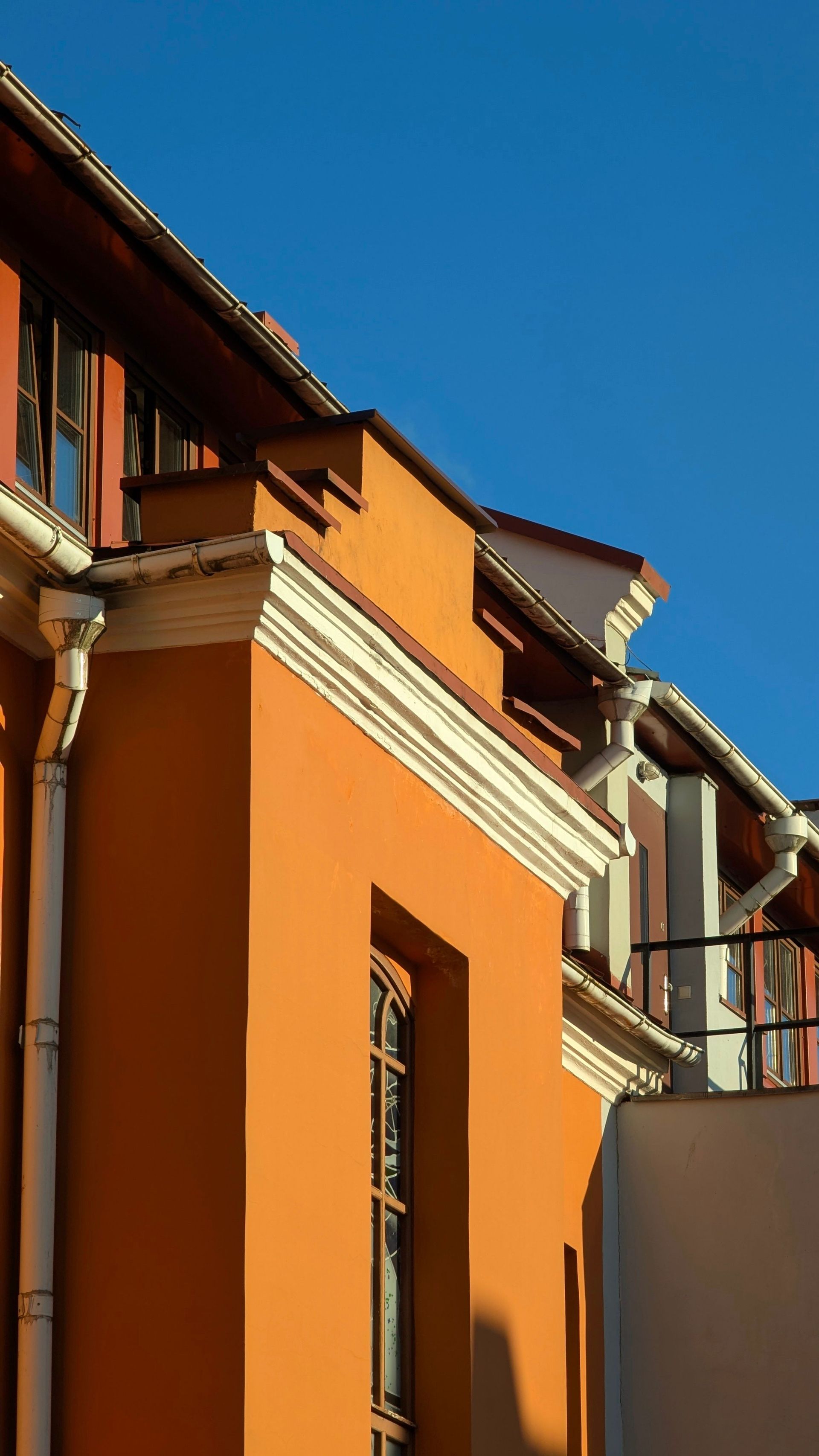 Stunning view of a modern building with an orange facade against a clear blue sky.