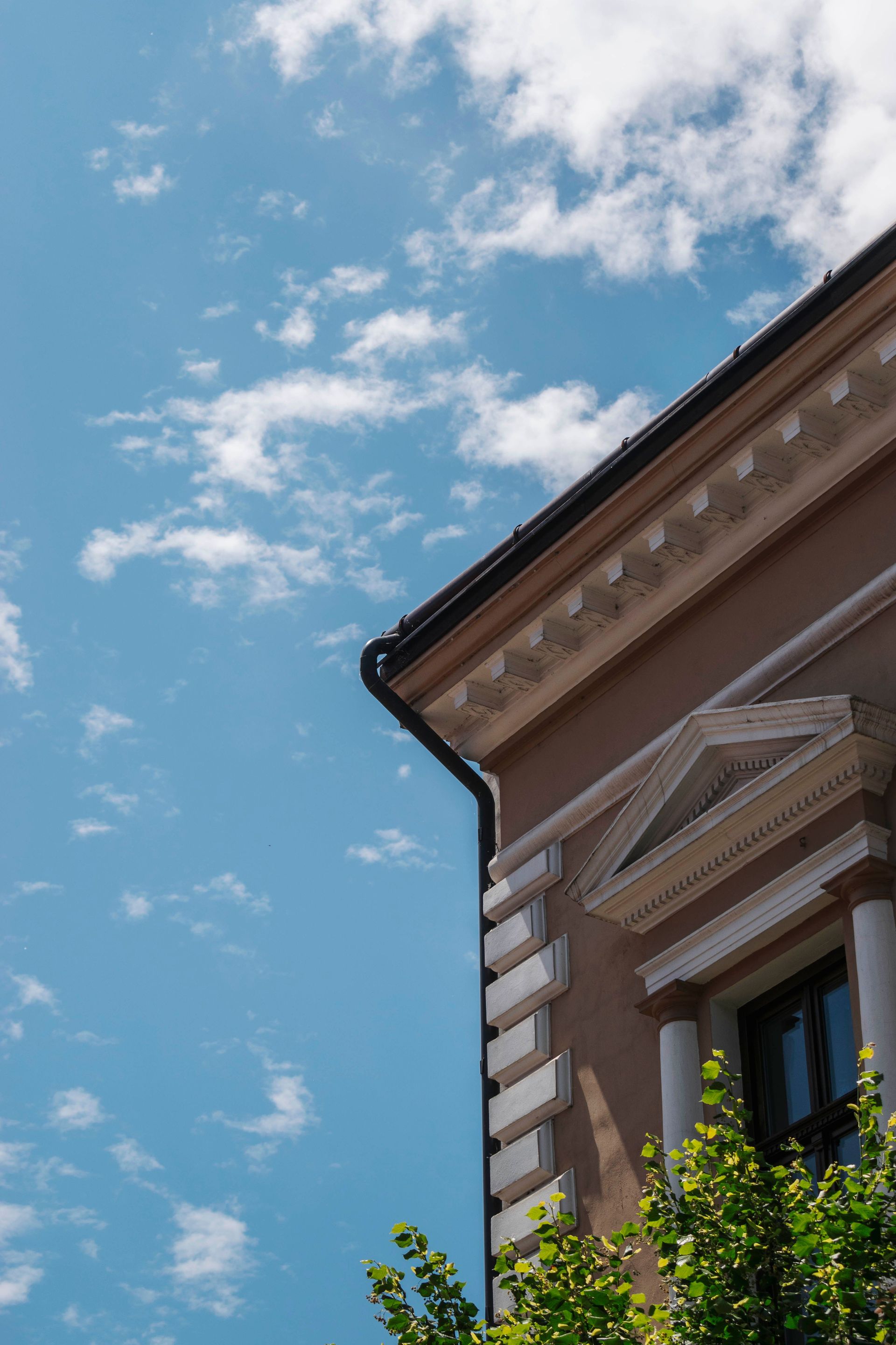 Classic European building facade with ornate details under blue sky with clouds.